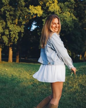 Milla farmerdzsekiben, napsütéses mezőn